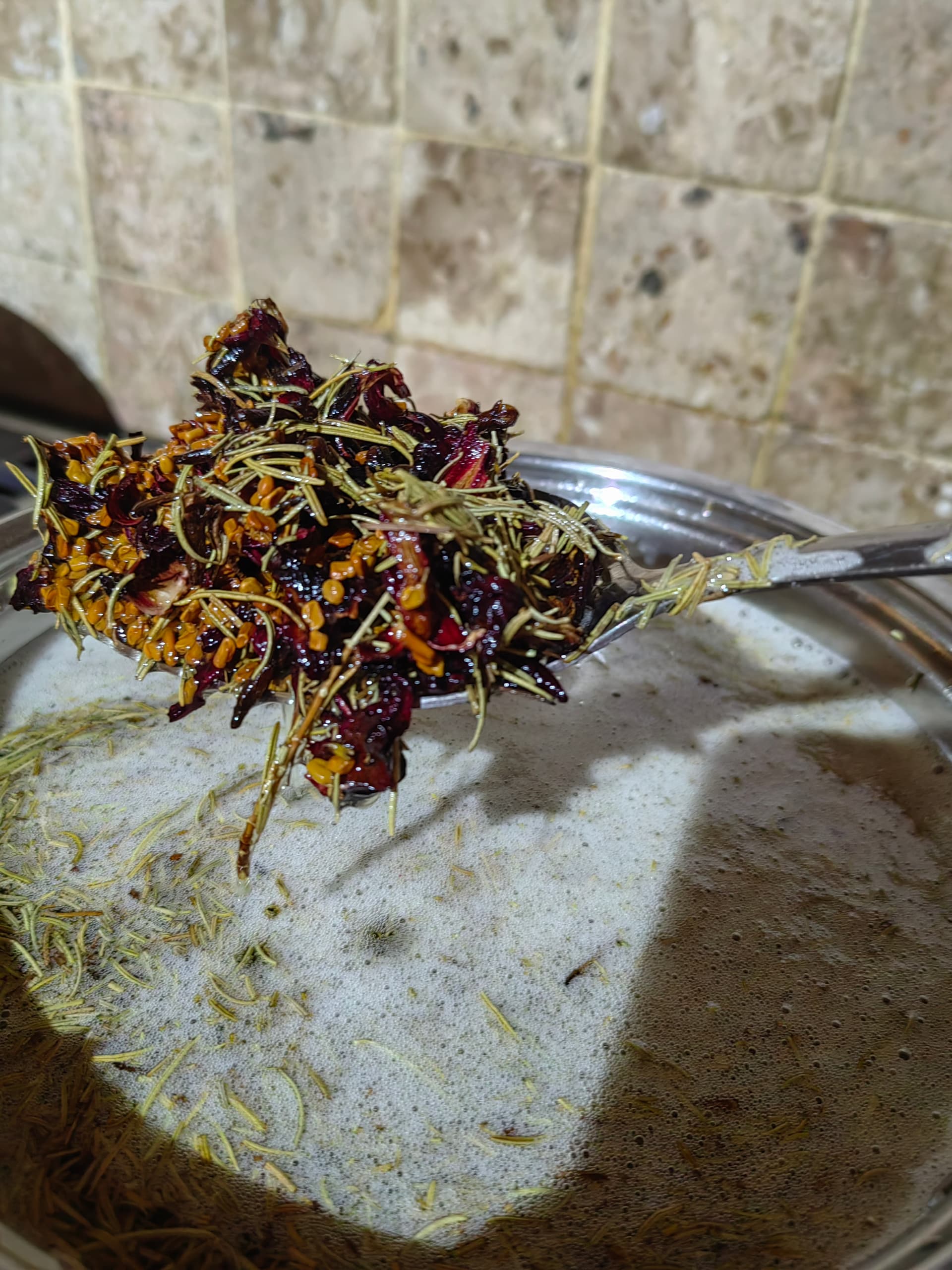 Whole botanicals lifted from the oil infusion — hibiscus, rosemary, fenugreek